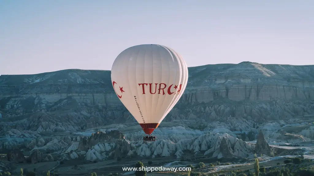 Hot air balloon flying above unique landscape of Cappadocia