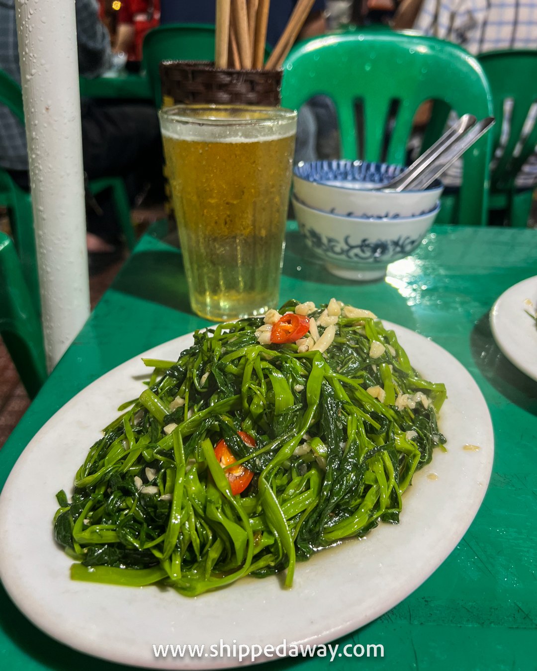 Morning glory (rau muống xào tỏi), sauteed water spinach with garlic, famous Vietnamese dish and Bia Hoi in Ba Dinh, Hanoi, Vietnam
