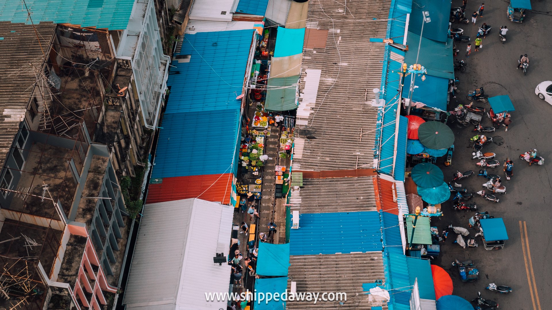 Drone view of train passing Maeklong Railway Market near Bangkok, Thailand
