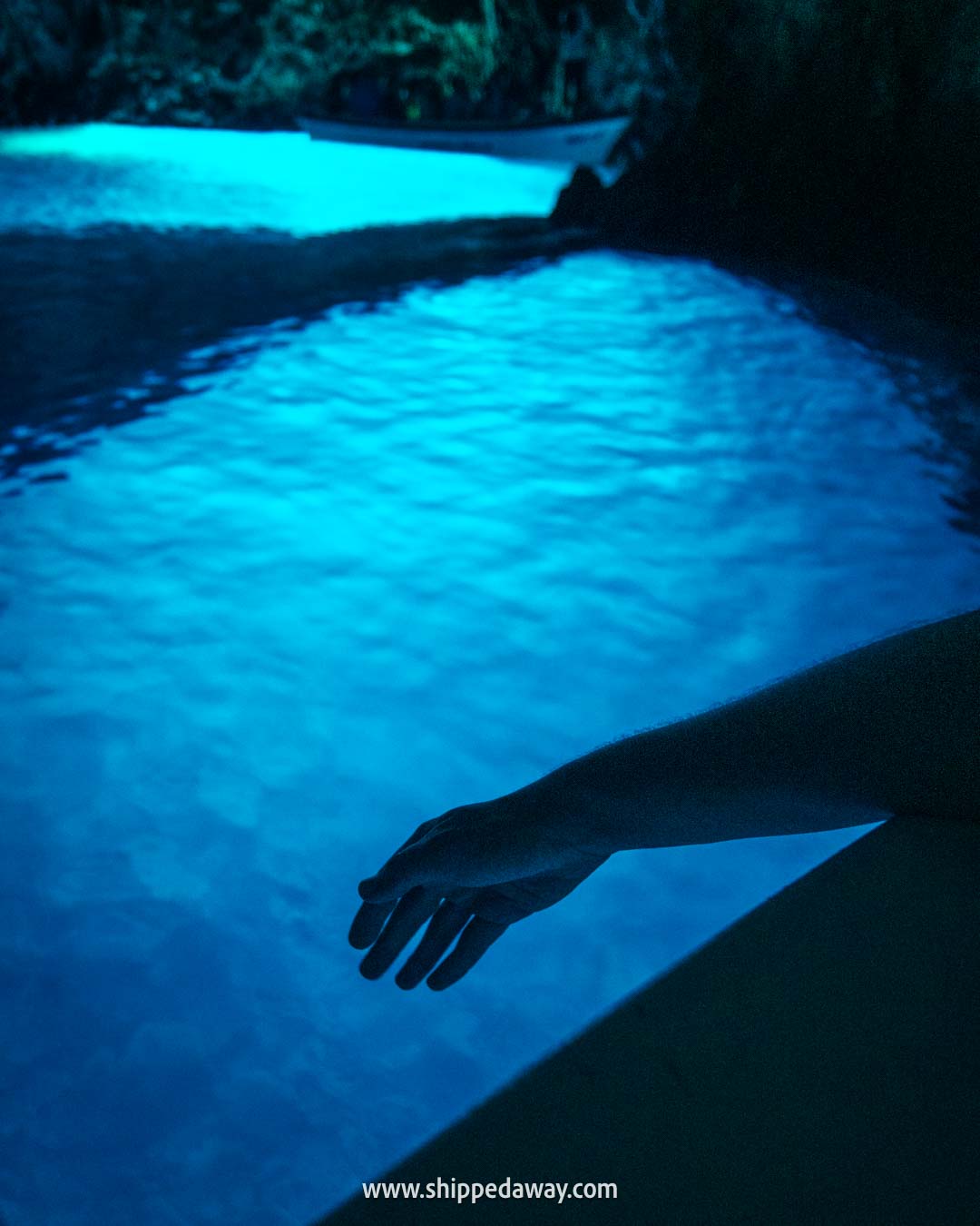 hand reaching to the blue water inside the Blue Cave Croatia - is Blue Cave in Croatia worth visiting - how to visit Blue Cave in Croatia - best Blue Cave tour
