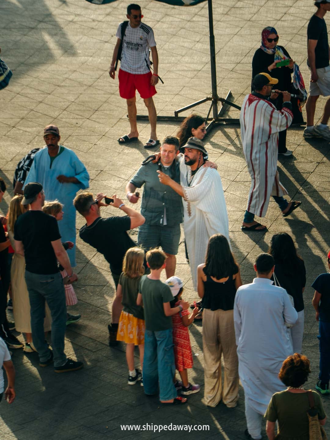 Things to do in Marrakesh, Morocco - tourists taking photos with snakes at Jemaa el-Fnaa square